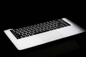 A modern laptop with a glowing keyboard illuminated in a dark, minimalist setting.
